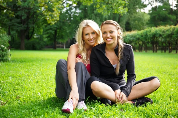Meninas atléticas sentadas em uma grama em um parque — Fotografia de Stock