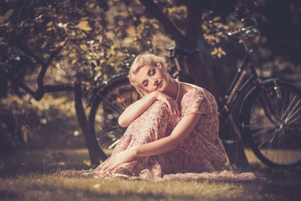 Mulher retro em vestido de verão sentado em um prado — Fotografia de Stock