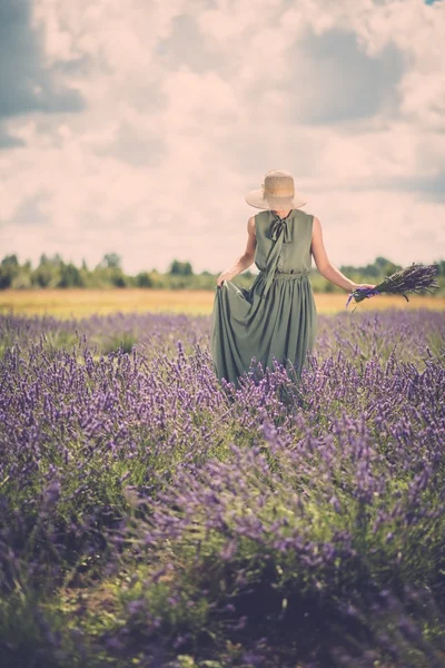 Vrouw in een lange groene jurk en hoed — Stockfoto