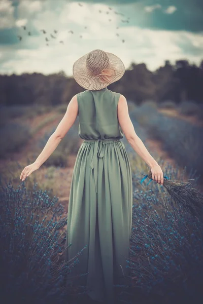 Kvinna i långa gröna klänning och hatt i ett lavendel fält — Stockfoto