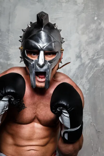 Man in boxing gloves and gladiator helmet — Stock Photo, Image