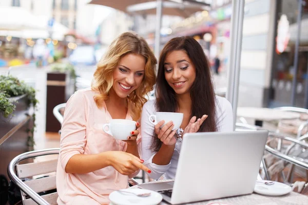 Dos hermosas chicas tazas y portátil en la cafetería de verano —  Fotos de Stock