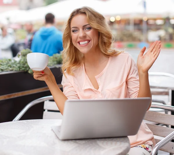 Uśmiechnięta młoda kobieta z kubkiem kawy i laptopa — Zdjęcie stockowe