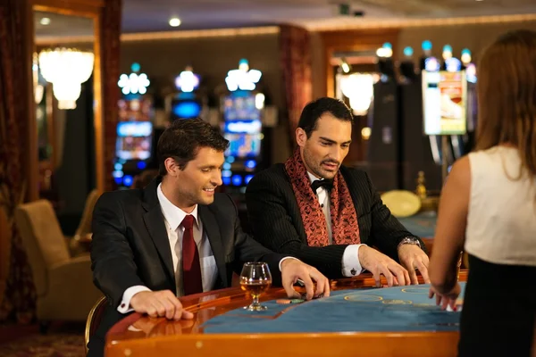 Двое молодых веселых мужчин за столом в казино — стоковое фото