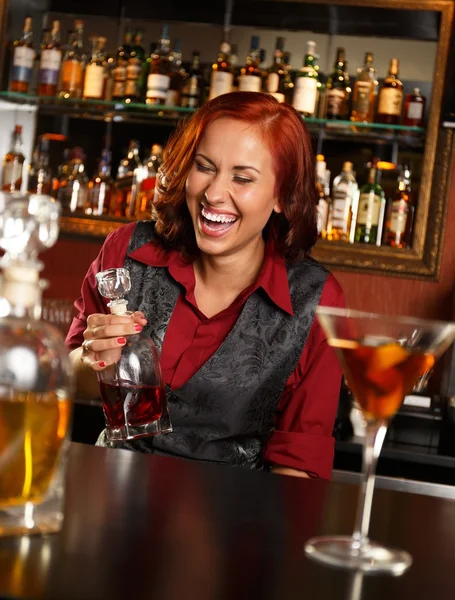 Belle barmaid rousse avec bouteille derrière le comptoir du bar — Photo