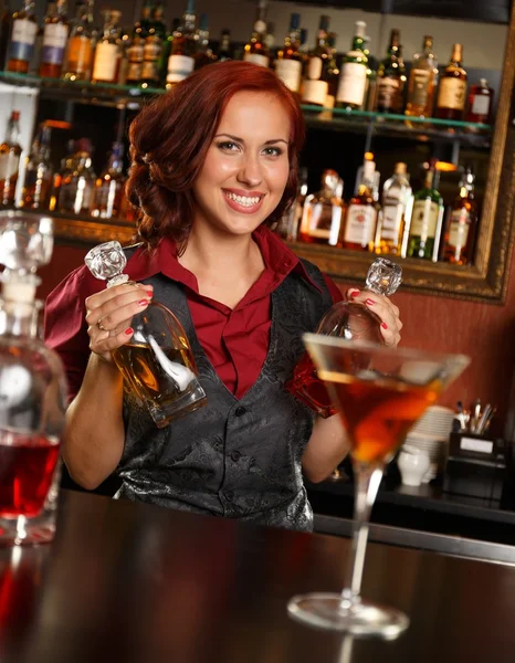 Hermosa camarera pelirroja con botella detrás del mostrador de la barra —  Fotos de Stock