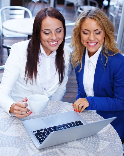 Two beautiful girls with laptop in summer cafe — Stock Photo, Image