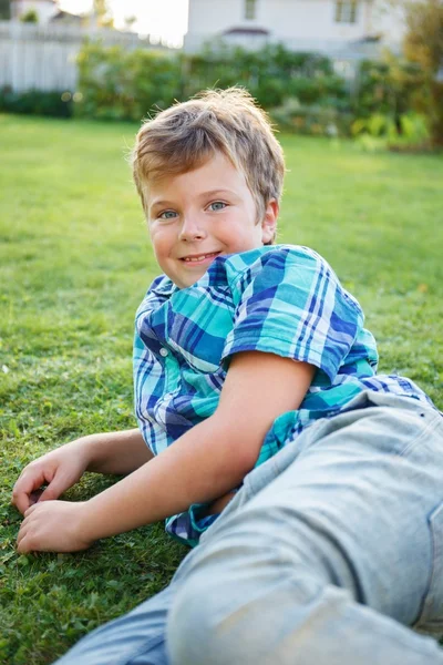 Positiver kleiner Junge liegt auf einer Wiese — Stockfoto