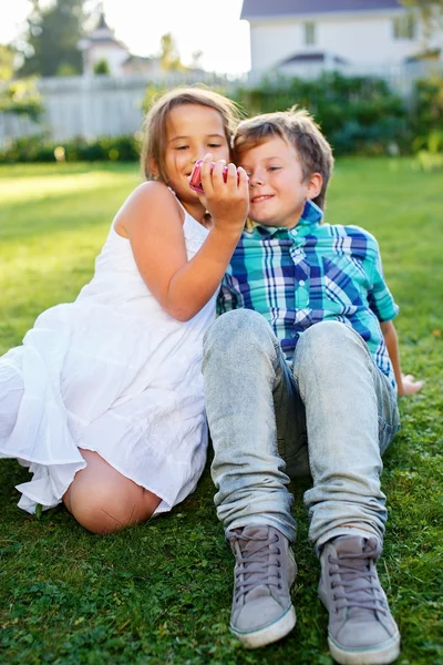 Happy children sitting on a meadow with mobile phone — Stock Photo, Image