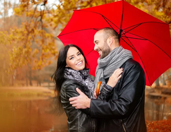 Felice coppia di mezza età con ombrello all'aperto nella bella giornata autunnale piovosa — Foto Stock