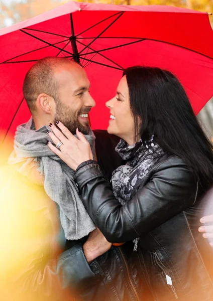 Счастливая пара средних лет с зонтиком на открытом воздухе в прекрасный дождливый осенний день — стоковое фото