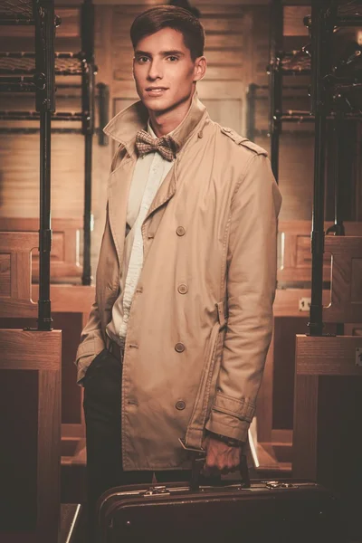 Beau jeune homme avec valise en manteau à l'intérieur du train ancien entraîneur — Photo