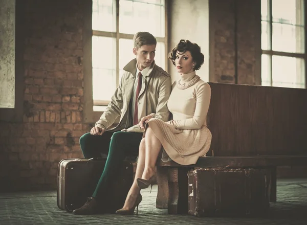 Beautiful vintage style young couple with suitcases on a train station — Stock Photo, Image