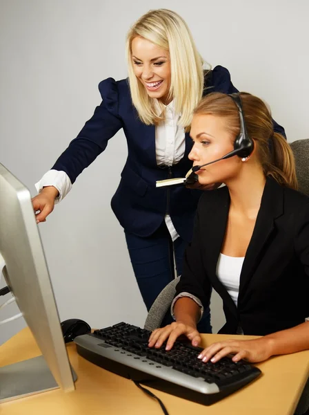 Beautiful help desk office support woman with female boss behind her — Stock Photo, Image