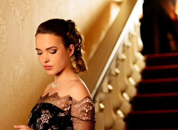 Close-up shot of a beautiful young girl in evening dress standing on a steps — Stock Photo, Image