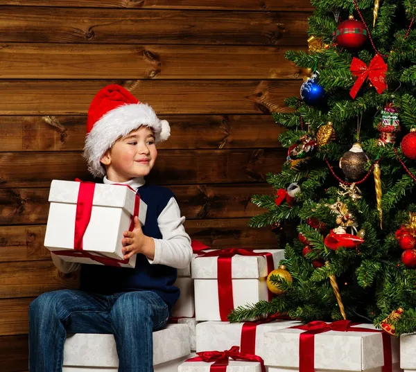 Kisfiú megnyitása a karácsonyfa alatt ajándék doboz — Stock Fotó