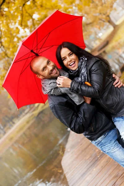 Heureux couple d'âge moyen avec parapluie à l'extérieur le beau jour d'automne pluvieux — Photo