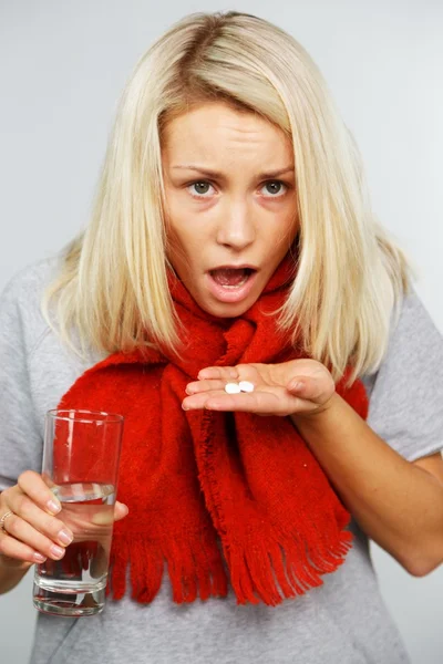 Sick young blond woman with pills and glass of water — Stock Photo, Image