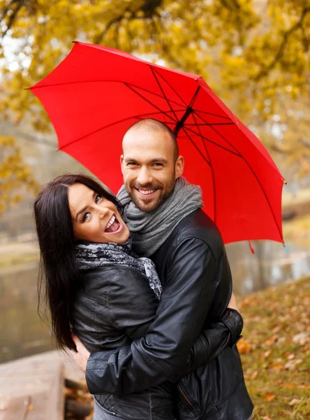 Felice coppia di mezza età con ombrello all'aperto nella bella giornata autunnale piovosa — Foto Stock