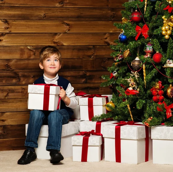 Liten pojke öppna presentförpackning under granen — Stockfoto