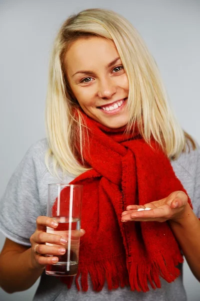 Mujer rubia joven enferma con pastillas y vaso de agua —  Fotos de Stock