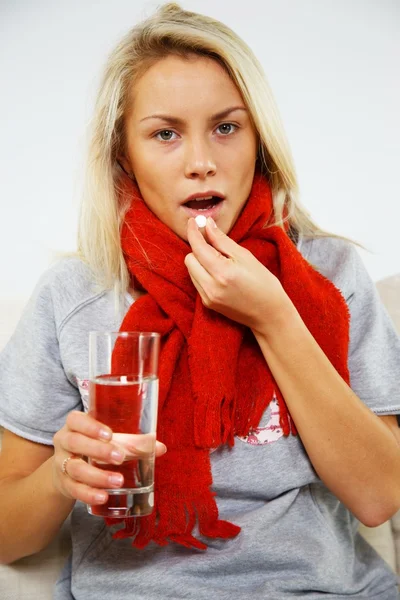 Sjuk ung blond kvinna med piller och glas vatten — Stockfoto