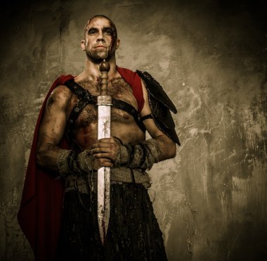 Wounded gladiator holding sword covered in blood with both hands clipart