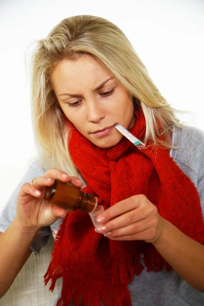 Sick young blond woman with thermometer bottle of mixture — Stock Photo, Image
