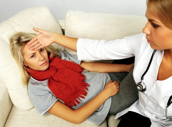 Médico feminino verificando a temperatura da menina doente com a mão — Fotografia de Stock