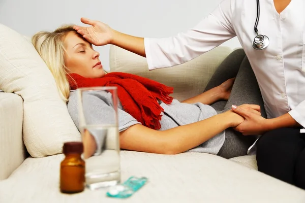 Médico feminino verificando a temperatura da menina doente com a mão — Fotografia de Stock