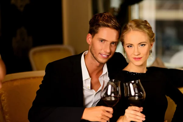 Beautiful young couple with glasses of wine in luxury interior — Stock Photo, Image