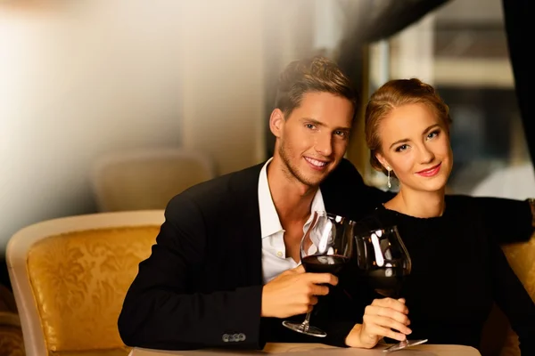 Beautiful young couple with glasses of wine in luxury interior — Stock Photo, Image