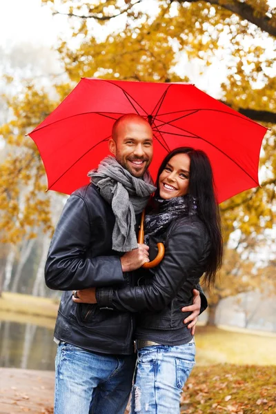 Happy middle-aged couple with umbrella outdoors on beautiful rainy autumn day — Stock Photo, Image