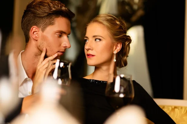 Mooie jonge paar met glazen wijn in luxe interieur — Stockfoto