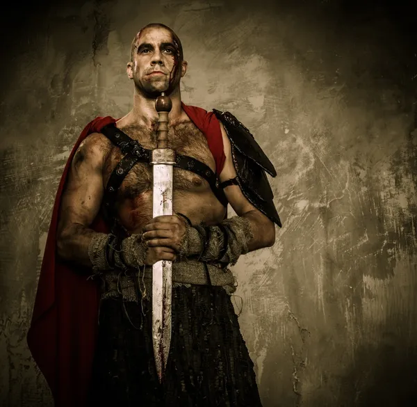Verwundeter Gladiator mit blutverschmiertem Schwert an beiden Händen — Stockfoto
