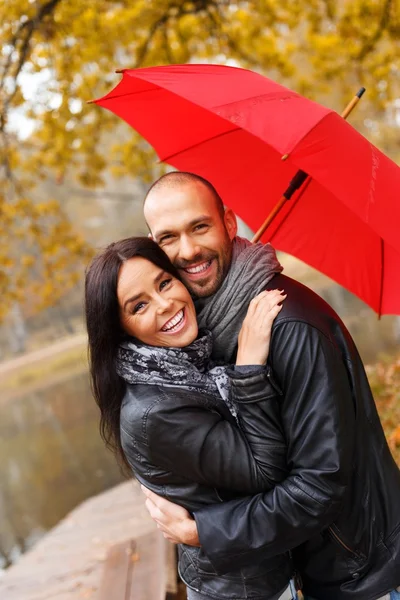 Feliz pareja de mediana edad con paraguas al aire libre en hermoso día de otoño lluvioso — Foto de Stock