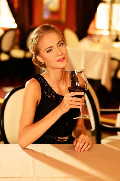 Όμορφη νεαρή κοπέλα με το ποτήρι κόκκινο κρασί, μόνο σε ένα εστιατόριο — Φωτογραφία Αρχείου