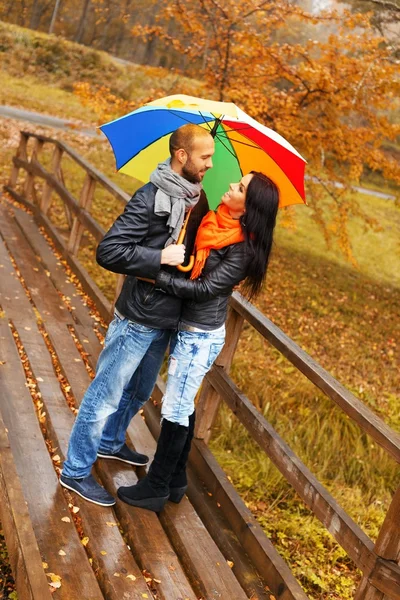 Šťastný pár středního věku s deštníkem venku na krásné deštivé podzimní den — Stock fotografie