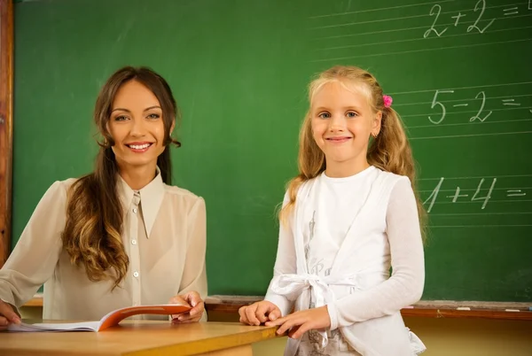 Weinig schoolmeisje beantwoorden in de buurt van schoolbord in school — Stockfoto