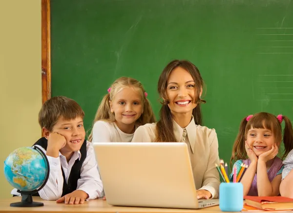 Groupe de camarades de classe heureux avec leur professeur en classe près du tableau noir — Photo