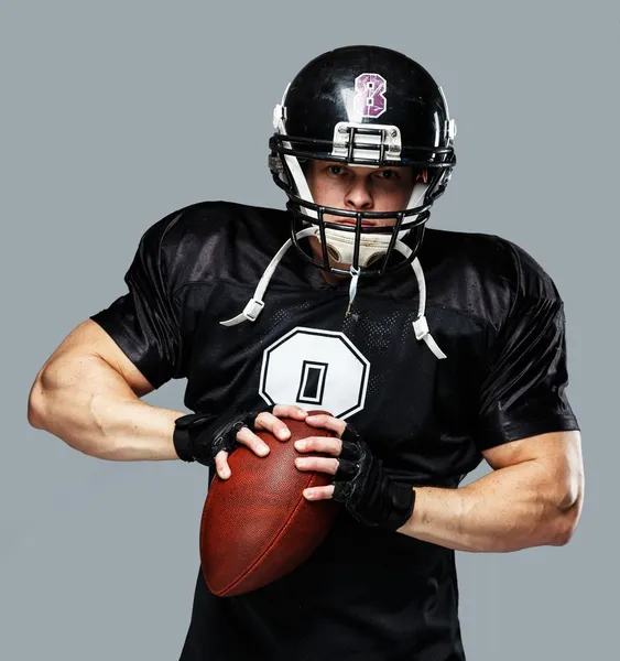 Amerikansk fotboll-spelare med boll bär hjälm och jersey — Stockfoto