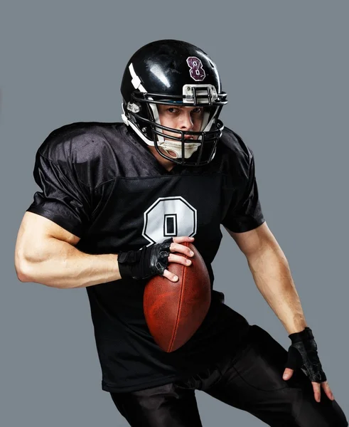 Jogador de futebol americano com bola usando capacete e camisa — Fotografia de Stock