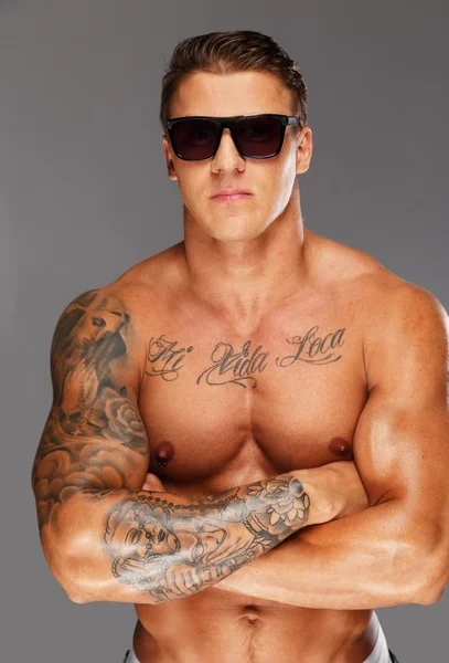 Stilig man solglasögon med muskulös tatuerad torso — Stockfoto