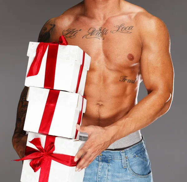 Человек с татуированным мускулистым туловищем с подарочными коробками — стоковое фото