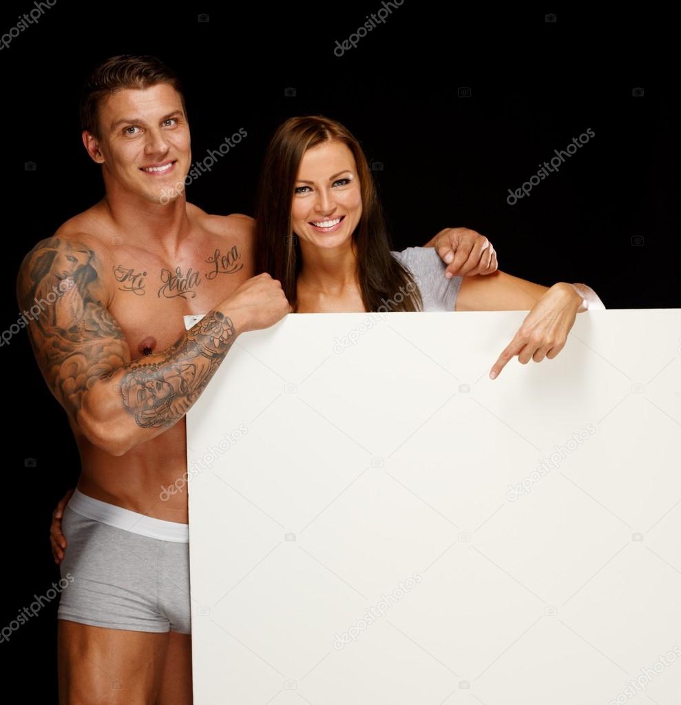 Man with muscular tattooed torso and woman holding blank notice board Stock Photo by ©nejron 36567011