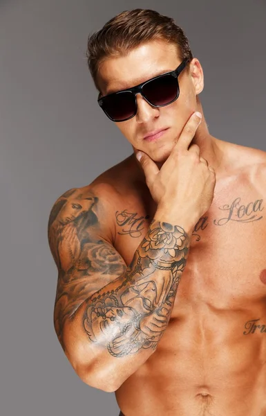 Hombre guapo en gafas de sol con torso musculoso tatuado — Foto de Stock