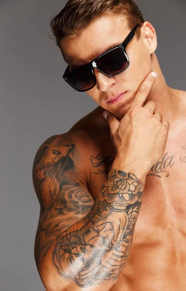 Hombre guapo en gafas de sol con torso musculoso tatuado —  Fotos de Stock