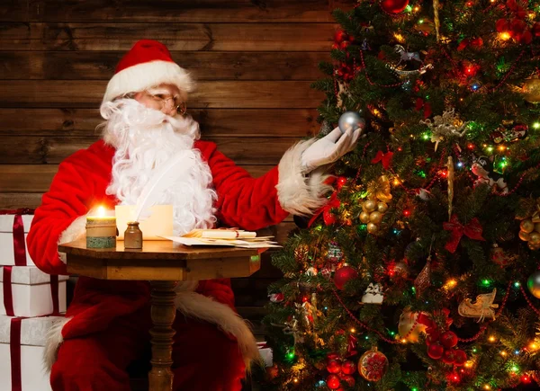 Άγιος Βασίλης ξύλινο σπίτι εσωτερικό εξετάζοντας στολισμένο χριστουγεννιάτικο δέντρο — Φωτογραφία Αρχείου