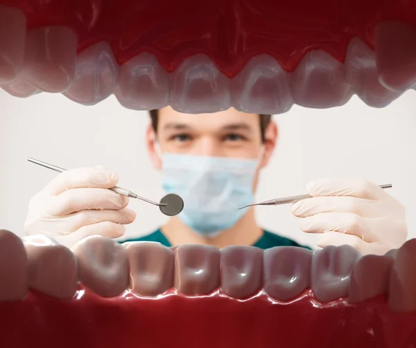 Ver en joven dentista masculino sosteniendo herramientas dentales de la boca del paciente —  Fotos de Stock