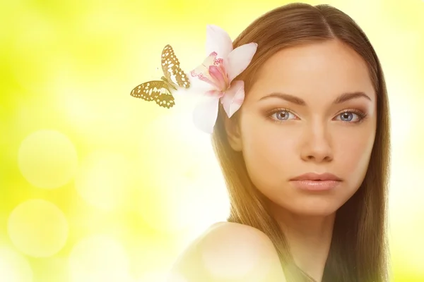Όμορφη νεαρή γυναίκα μελαχρινή με μπλε μάτια και πεταλούδα που κάθεται στο ορχιδέα λουλούδι στα μαλλιά της — Φωτογραφία Αρχείου